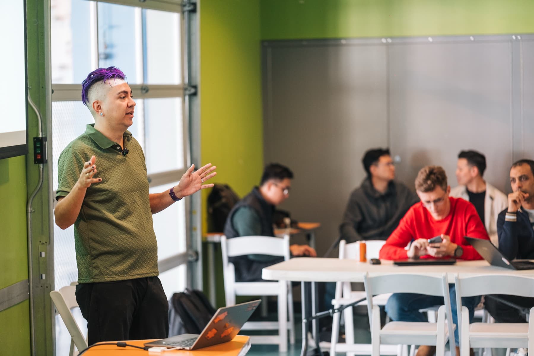 Gabriel Velazquez leading a hands-on workshop, gesturing to attendees seated at laptops